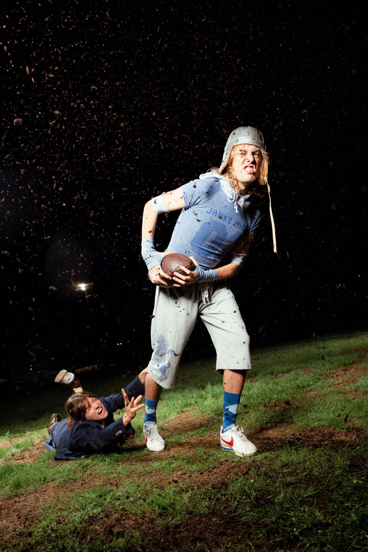 Janky Inc. Limited — a football player in a Janky Inc. 01 tee and silver helmet tackled from behind amid flying dirt
