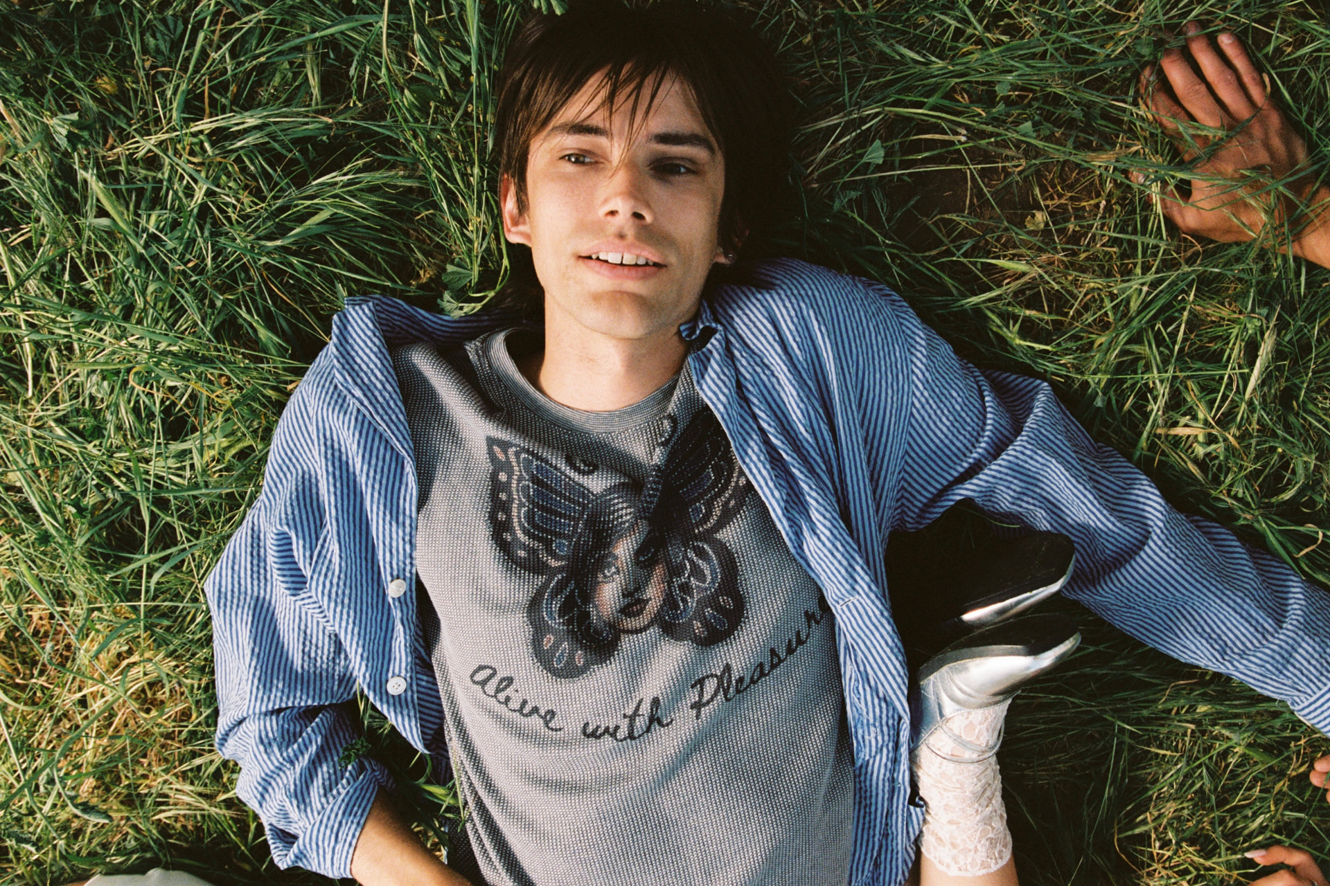 Janky Inc. SS25 — young man lying relaxed in green grass
