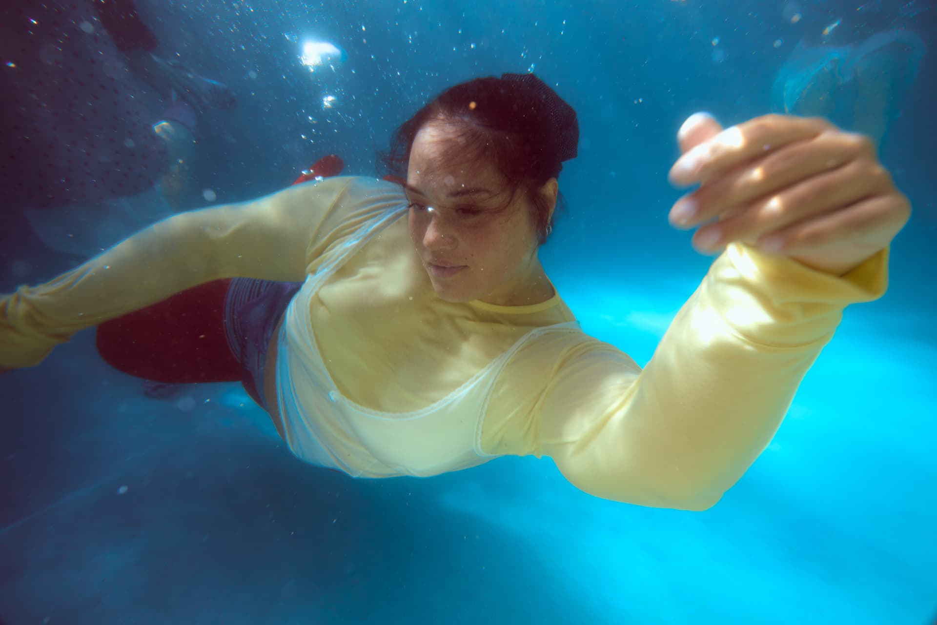 GOODBYE SUMMER — a swimmer in a yellow shirt and red leggings through bubble-filled water