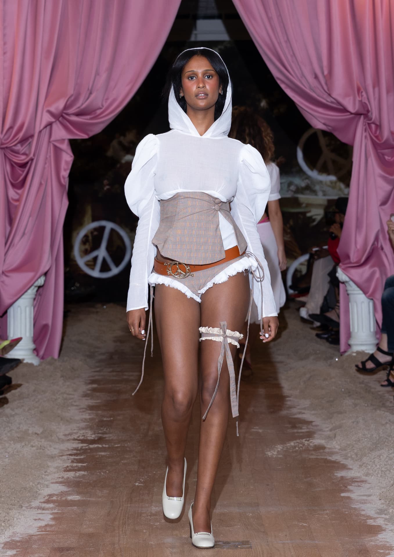 Ella Mae SS27 — white hooded puff-sleeve top with a plaid corset and ruffled shorts