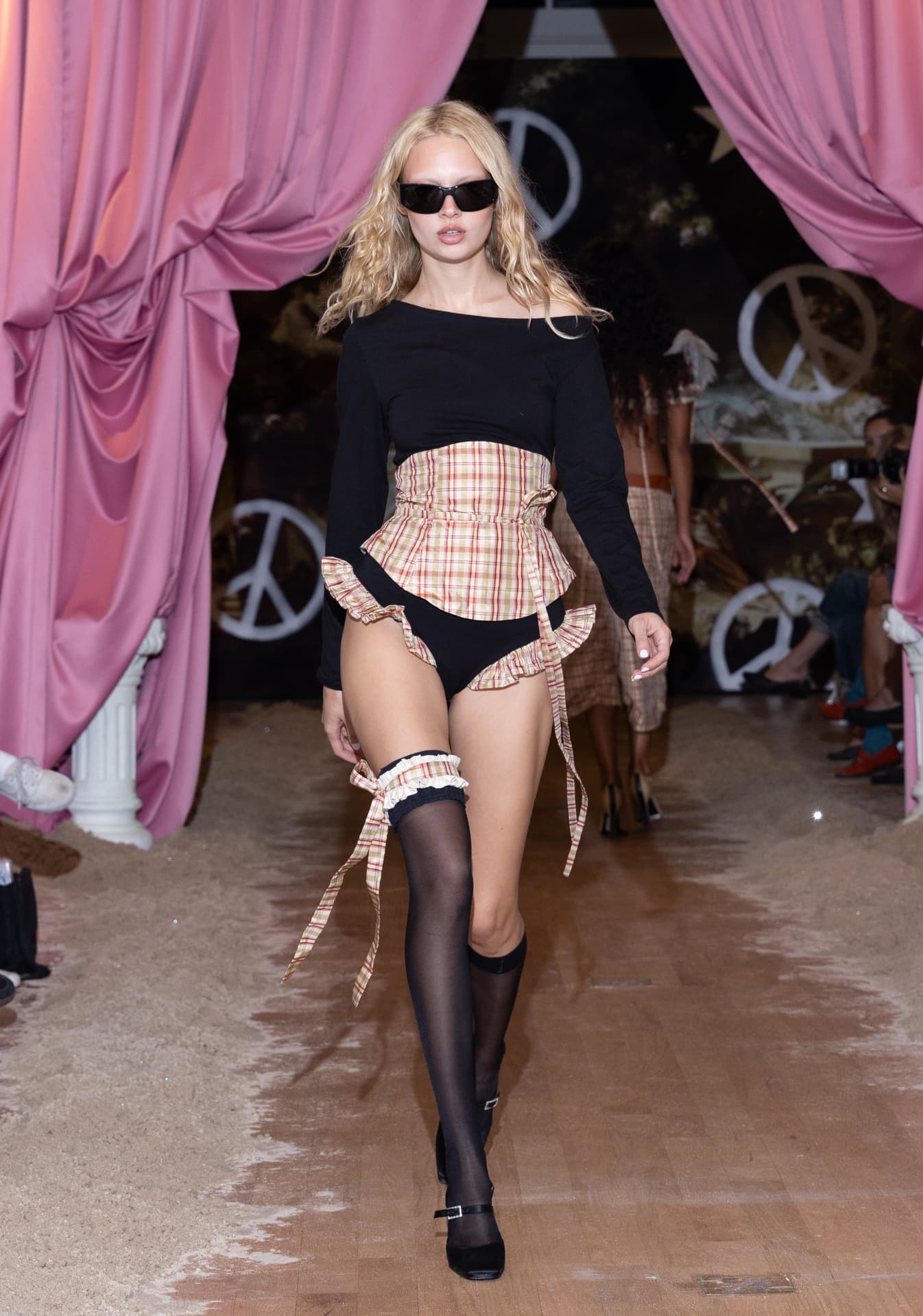 Ella Mae SS27 — black long-sleeve top under a ruffled plaid corset with Mary Janes