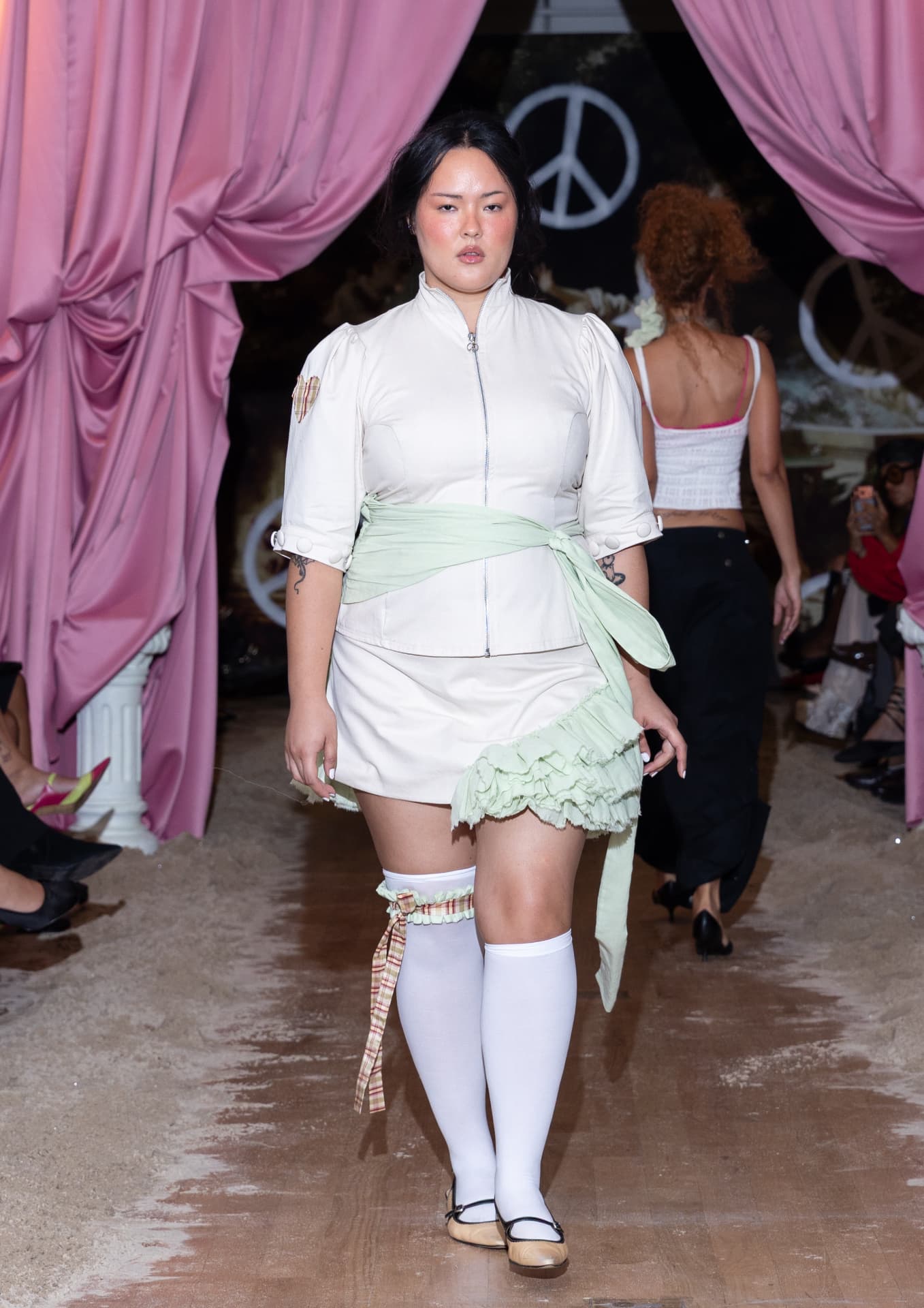 Ella Mae SS27 — off-white zip-up jacket with a green ruffled mini skirt