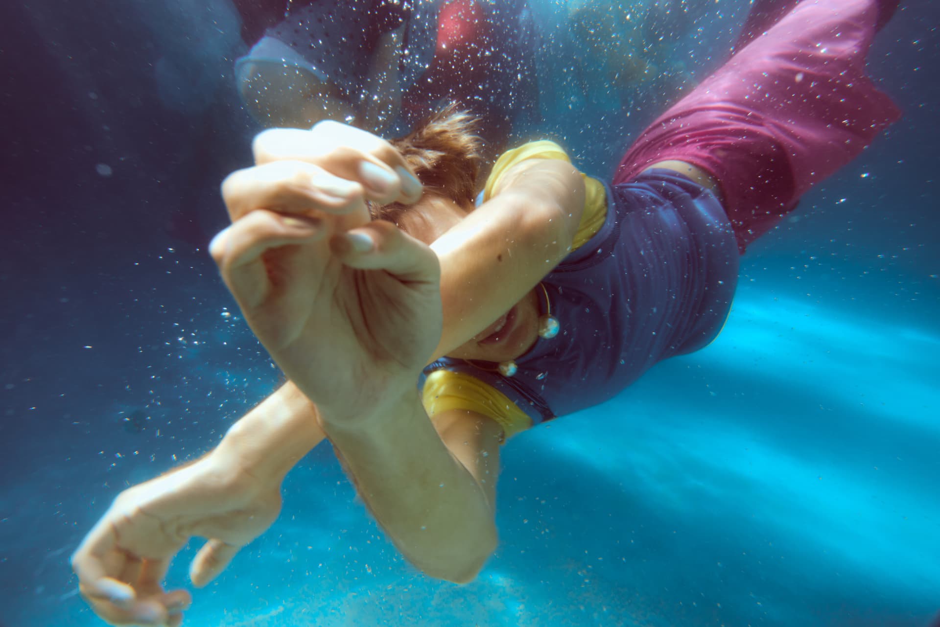 GOODBYE SUMMER — a swimmer reaching toward the camera through a cloud of bubbles